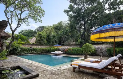a swimming pool in a yard with a bench at The Oberoi Beach Resort, Bali in Seminyak