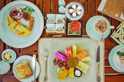 a table with plates of food and a cup of coffee at The Oberoi Beach Resort, Bali in Seminyak