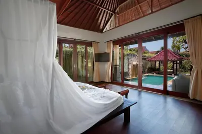 a bedroom with a white bed and a pool at Bali Prime Villas Seminyak by Kanaya Hospitality in Seminyak