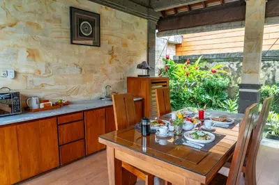 a kitchen with a wooden table and a table and chairs at Bali Prime Villas Seminyak by Kanaya Hospitality in Seminyak