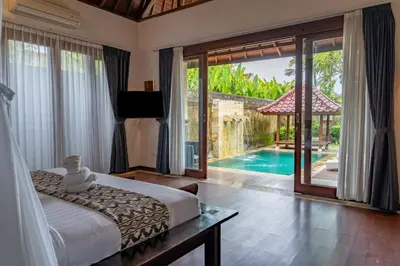 a bedroom with a bed and a view of a pool at Bali Prime Villas Seminyak by Kanaya Hospitality in Seminyak