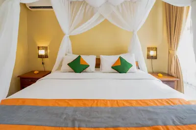 a bedroom with a large white bed with two lamps at Desamuda Village by Pertama Management in Seminyak