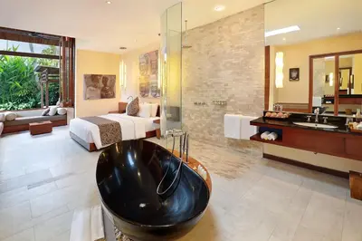 a bathroom with a large black tub in front of a bedroom at The Elysian Boutique Villa Hotel in Seminyak