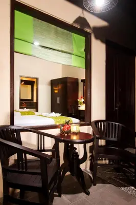 a room with a table and chairs and a bed at Bali Ayu Hotel & Villas in Seminyak