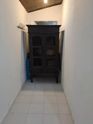 a hallway with a black cabinet and a white tile floor at Shalana Homestay- formerly Teka Teki House in Seminyak