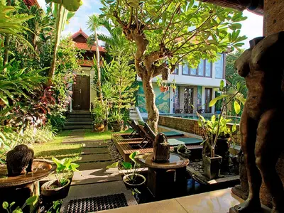 a garden with trees and potted plants and a building at Umah Watu Villas in Seminyak
