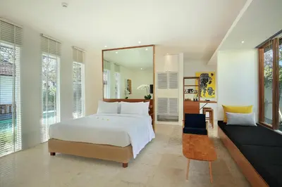 a bedroom with a large white bed and a mirror at Uma Sapna Seminyak in Seminyak