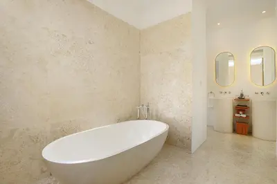 a white bath tub in a bathroom with two mirrors at Uma Sapna Seminyak in Seminyak
