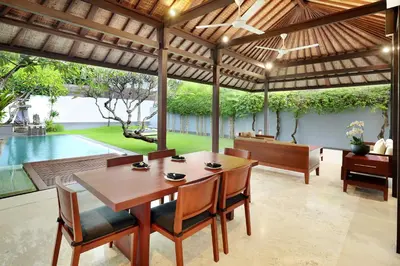 a dining room with a table and chairs and a pool at Uma Sapna Seminyak in Seminyak