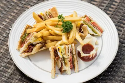 a plate of food with a sandwich and french fries at Royal Hotel and Villa Bali in Legian