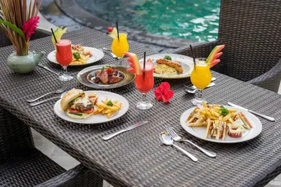 a table with plates of food and drinks on it at Royal Hotel and Villa Bali in Legian