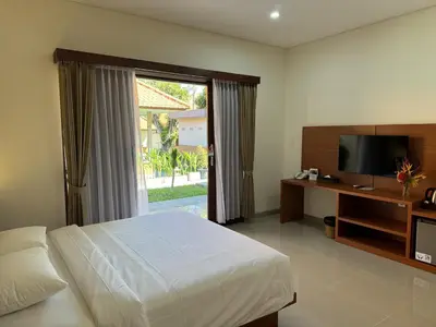 a bedroom with a bed and a flat screen tv at New Garden View Resort in Legian
