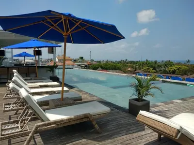 a deck with chairs and an umbrella and a swimming pool at New Garden View Resort in Legian