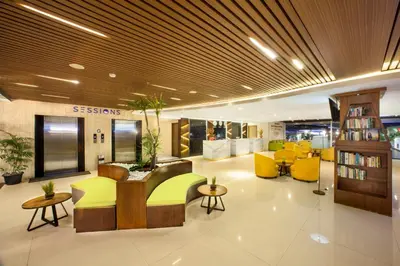 a lobby with a library with yellow chairs and tables at New Garden View Resort in Legian
