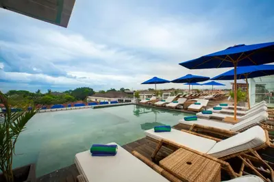 a swimming pool with lounge chairs and umbrellas at New Garden View Resort in Legian
