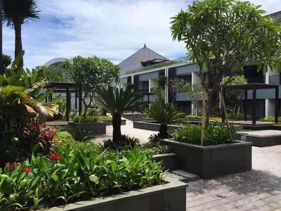 a building with trees and plants in front of it at Aryaduta Bali in Kuta