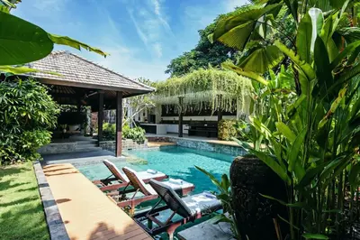 a swimming pool with chairs and a gazebo at Villa Besok in Seminyak