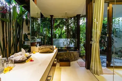 a bathroom with a tub and a sink and a bathroom with plants at Villa Besok in Seminyak