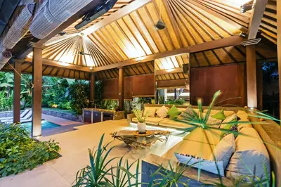 an outdoor living room with a large wooden pergola at Villa Besok in Seminyak