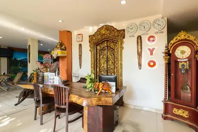 a dining room with a table and a clock on the wall at Capital O 1666 Grand Pudjawan Hotel Near Kuta Beach in Kuta