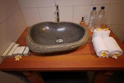 a bathroom sink with towels on a wooden table at Mina Pelasa Hotel in Legian