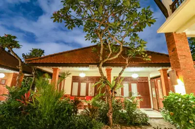 a house with a tree in front of it at Mina Pelasa Hotel in Legian