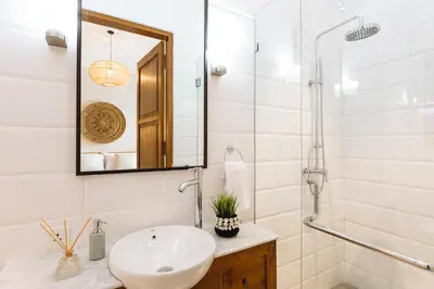a white bathroom with a sink and a mirror at Puri Pani in Seminyak