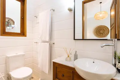 a white bathroom with a sink and a toilet at Puri Pani in Seminyak