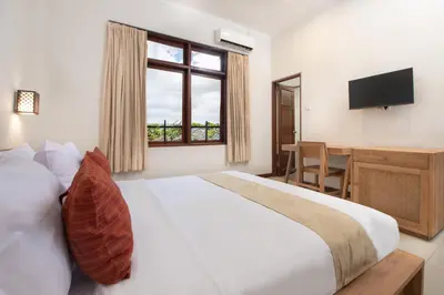 a bedroom with a large bed and a television at Villa Bunga Hotel in Seminyak