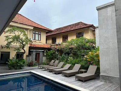 a patio with lounge chairs and a swimming pool at Villa Bunga Hotel in Seminyak
