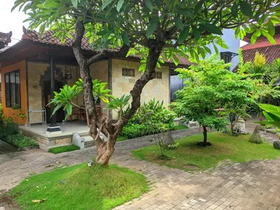 a house with two trees in front of it at Taman Sari Cottages in Kuta