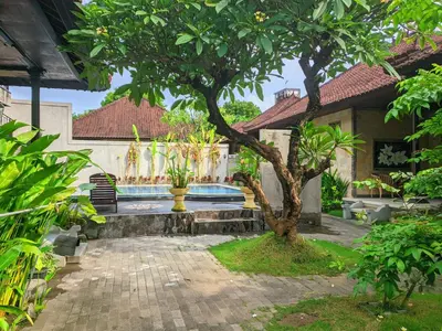 a courtyard with a tree and a swimming pool at Taman Sari Cottages in Kuta