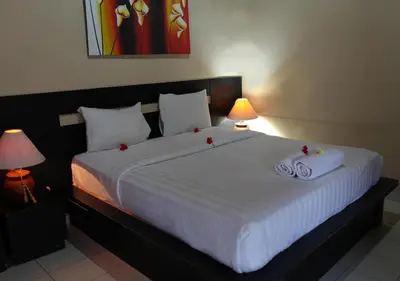 a bedroom with a large white bed with two towels at Taman Sari Cottages in Kuta