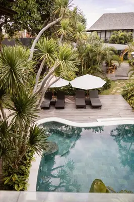 a pool with a table and chairs and palm trees at Wave House Resort Canggu in Canggu