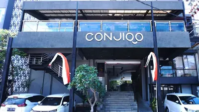 a car dealership with cars parked in front of it at Conjioo Hotel Kuta Managed By MHM in Legian