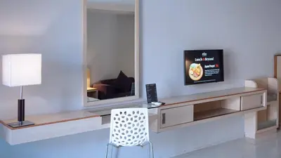 a living room with a mirror and a chair at Conjioo Hotel Kuta Managed By MHM in Legian