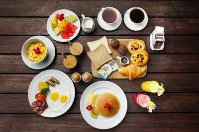a wooden table with plates of breakfast foods and coffee at Chandra Bali Villas in Seminyak