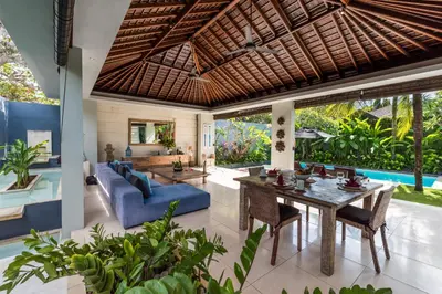 an open living room with a blue couch and a table at Kembali Villas in Seminyak