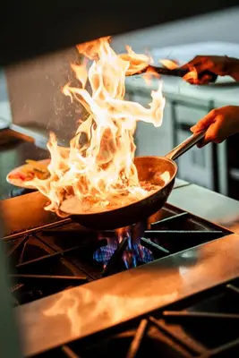 a person cooking food in a pan on a stove at Tonys Villas & Resort Seminyak - Bali in Seminyak