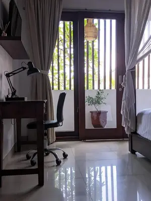 a bedroom with a desk and a bed and a window at Dim House Jimbaran in Jimbaran