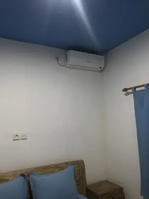a room with a ceiling with a heater and a couch at Turtle Island Homestay in Sanur