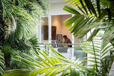 a woman sitting at a table in a room with plants at Villa Bebek in Seminyak