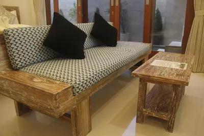 a bench with pillows on it with a table at Green Studio Apartment Seminyak in Seminyak
