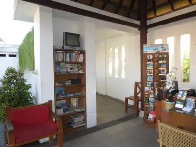 a living room with a red chair and book shelves at Seminyak TownHouse in Legian