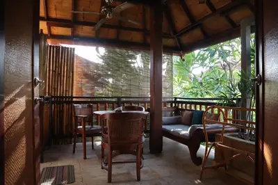 a porch with a couch and a table and chairs at Pondok Agung Bed & Breakfast in Nusa Dua