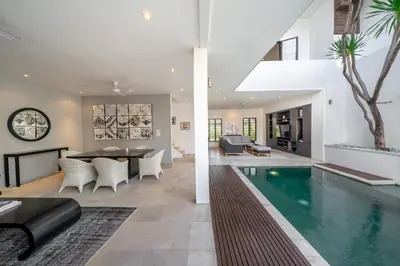 a living room with a swimming pool and a dining room at The Town House in Seminyak