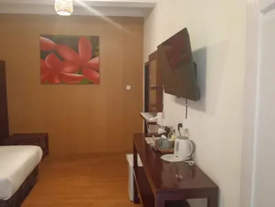 a room with a bed and a tv and a desk at City Garden Bali Dwipa Hotel, Kuta in Kuta