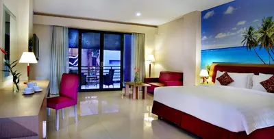 a hotel room with a large bed and a balcony at Kuta Central Park Hotel in Kuta