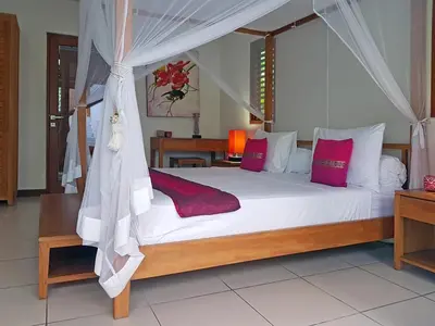 a bedroom with a large white bed with red pillows at Villa Kakariki in Kerobokan