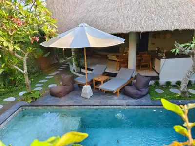 a resort with a swimming pool and an umbrella at SuB Villas Bali in Canggu